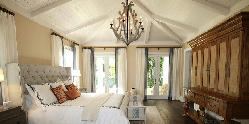 Cosy upholstered bed with soft pillows beside a stylish cabinet in a warm hotel room.