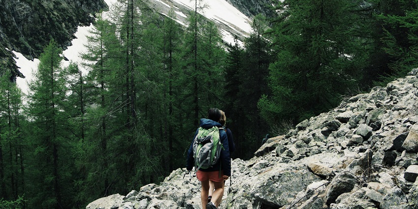 A landscape of a man standing in the middle of a mountain range during the daytime.