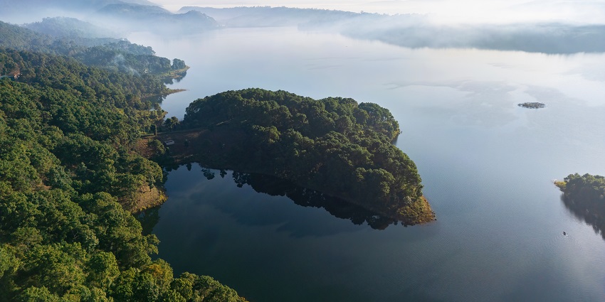 Aerial view of Umiam Lake in Meghalaya, India, with clear blue water surrounded by green hills.