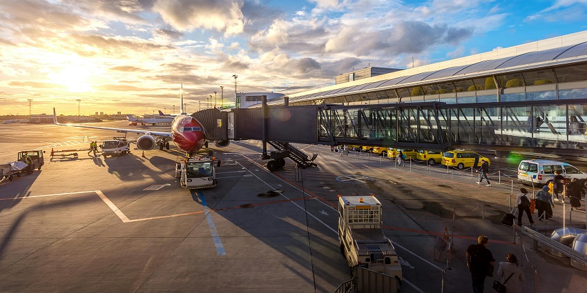 A vibrant red aeroplane parked on a runway, ready for takeoff against a clear sky.