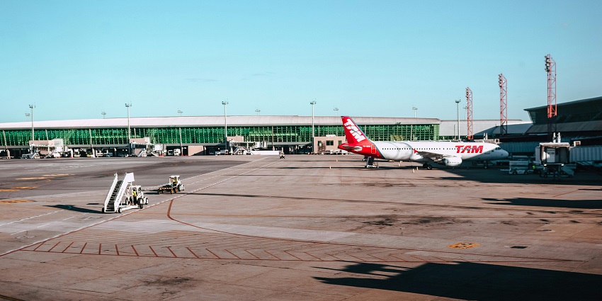 A white and red aeroplane parked at an airport, ready for takeoff against a clear blue sky.