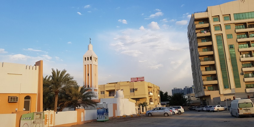 A picture of a historical mosque in Ajman, with vehicles parked in the parking area