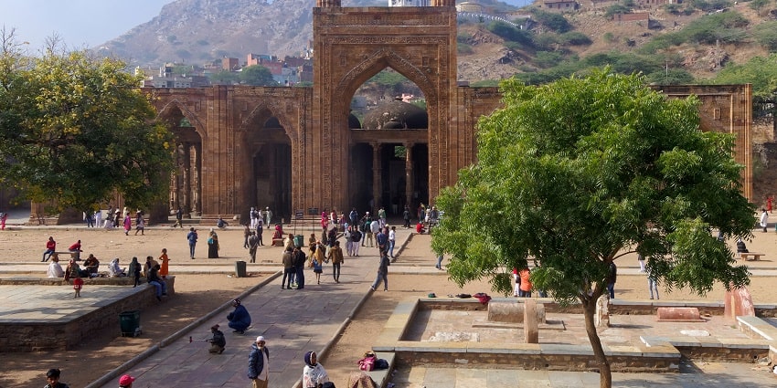 A picture of a historical monument in Ajmer with people spread around in groups to explore
