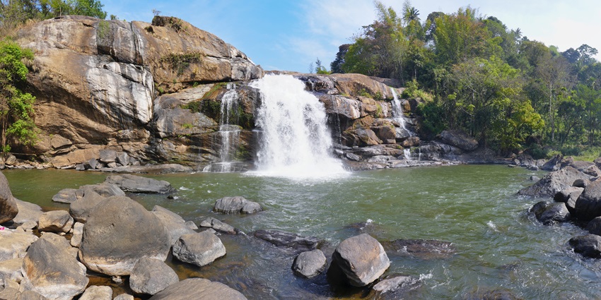 A picture of a waterfall with water cascading down a rocky terrain into a river