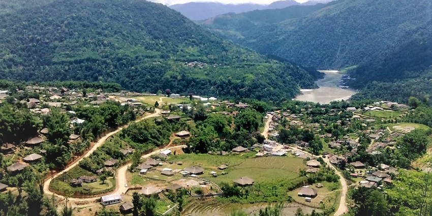 A picture of a village with green lands, trees and a scenery