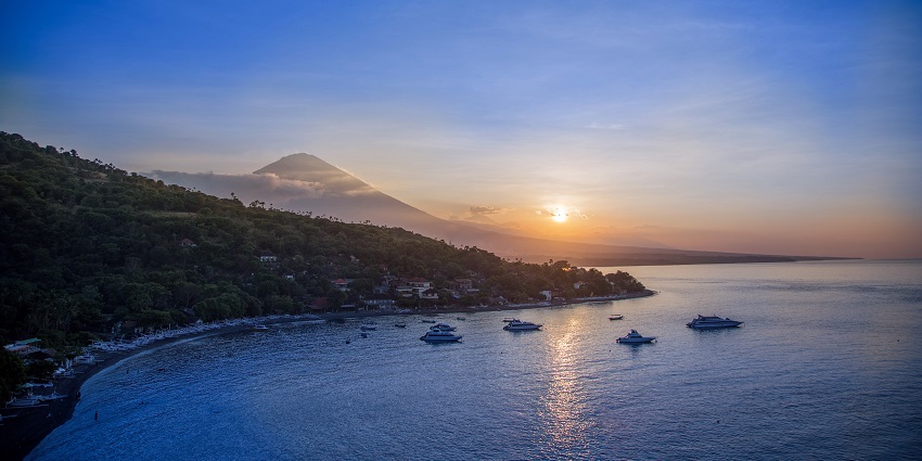 A beautiful picture of a sunset in Bali with the sea and mountains visible