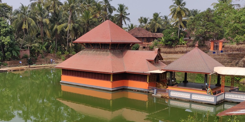 A picture of a scenic temple built in the middle of a lake near the Malom Wildlife Sanctuary
