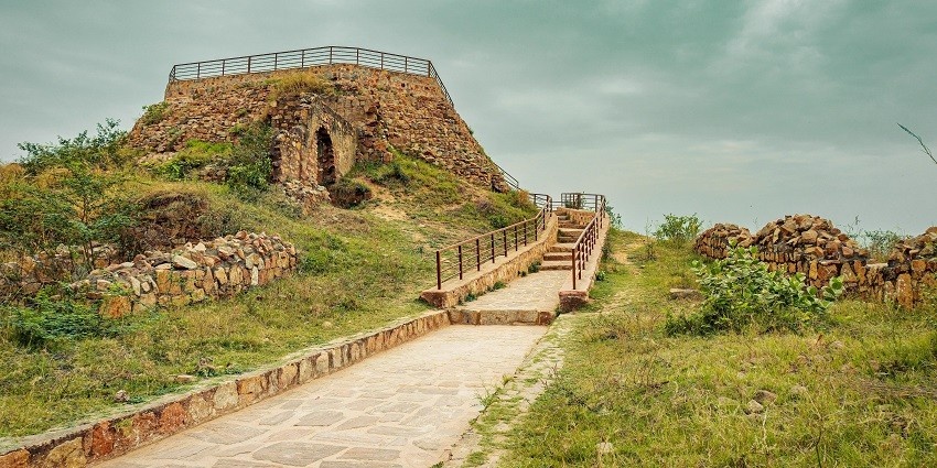 Ancient stone fort ruins surrounded by lush greenery under a clear blue sky.