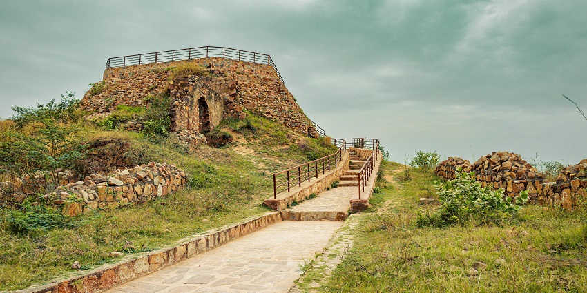 Ancient stone fort ruins surrounded by lush greenery and a clear blue sky.