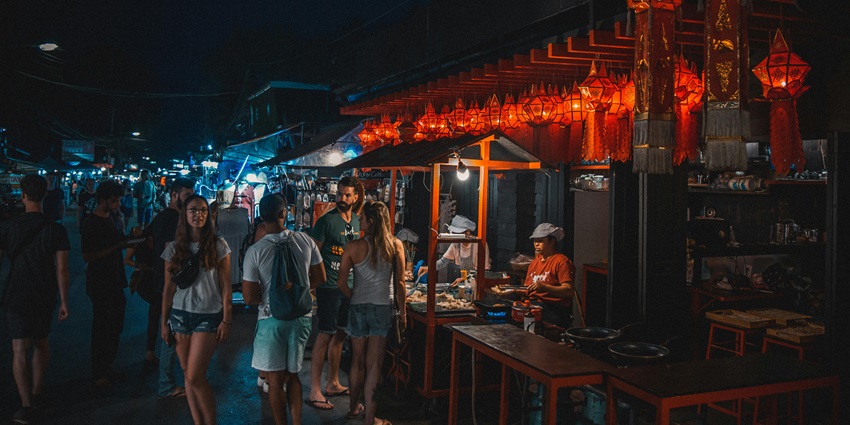 People walking past storefronts on a busy shopping street with evening lights.