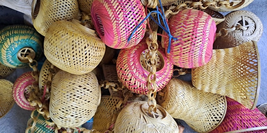 A mesmerising view of different colourful bamboo crafts displayed for sale during the day.