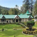 A picture of a Colonial-era building situated amidst green mountains and tall trees