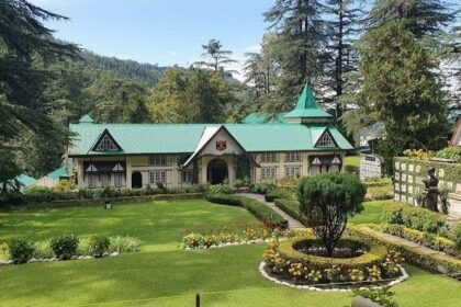 A picture of a Colonial-era building situated amidst green mountains and tall trees