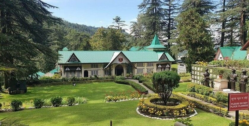 A picture of a Colonial-era building situated amidst green mountains and tall trees