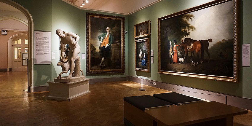 A picture of an art gallery with a sculpture and multiple art pieces kept on display for visitors and art admirers