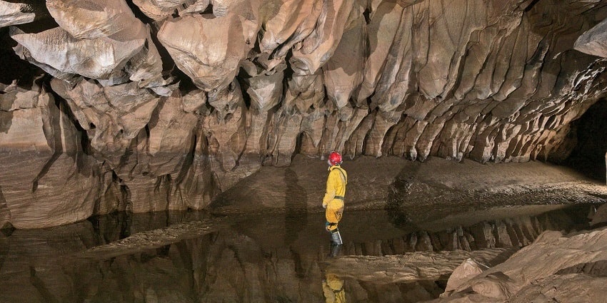 Spleogens WV cave, showcasing unique stalactites and stalagmites in a dark chamber.