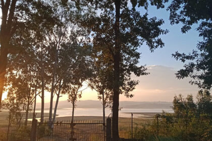 A scenic view of sunset in Umramgso in Assam with a backdrop of mountains and a lake.