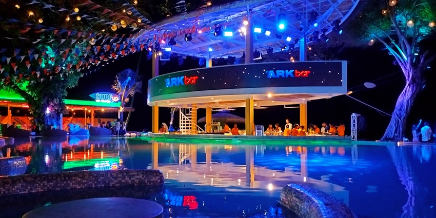 A picture of a beach resort with a swimming pool in Thailand taken at night, with blue hues all around