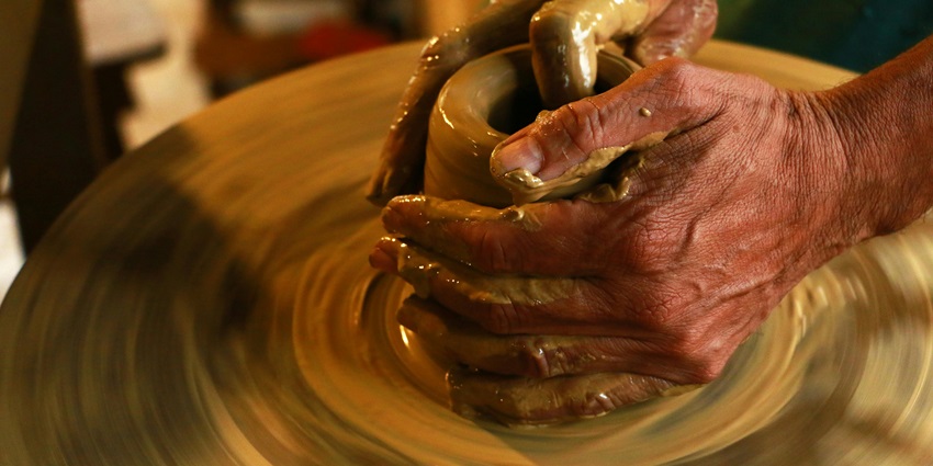 Hands shaping clay on pottery wheel, highlighting craftsmanship in a focused studio setting, one of the best things to do in Delhi for couples.