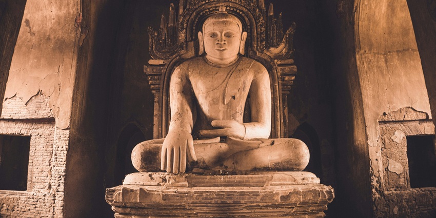 Large Buddha statue set against a grey, minimalist architectural background