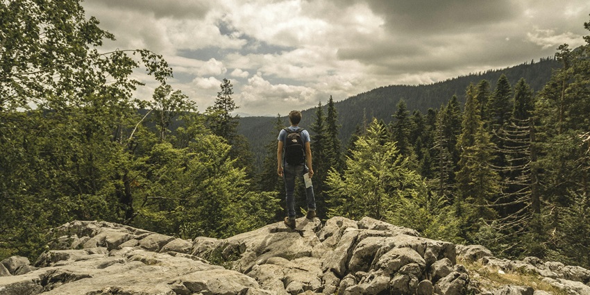 Man standing on a cliff, taking in the expansive view, part of a hiking experience.