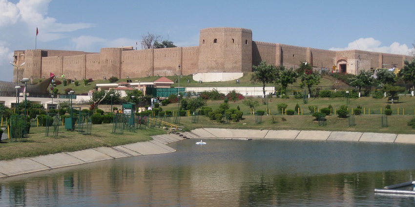 Scenic view of Bahu Fort with lush greenery and a clear blue sky in the background.