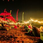 A breathtaking view of Bali with red umbrellas and yellow light near a beach at night.