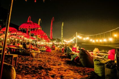 A breathtaking view of Bali with red umbrellas and yellow light near a beach at night.