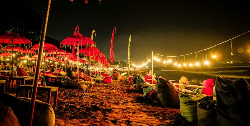 A breathtaking view of Bali with red umbrellas and yellow light near a beach at night.