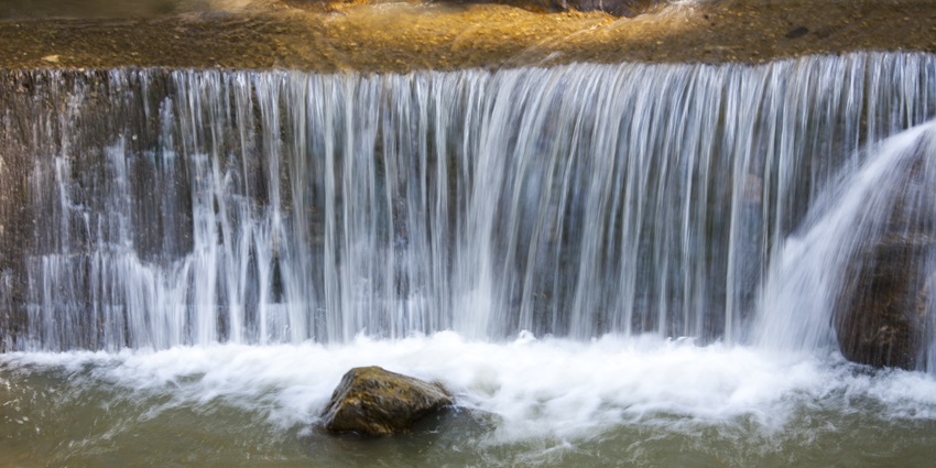 A picture of a scenic waterfall with water cascading down a hill into a pond in Gangtok