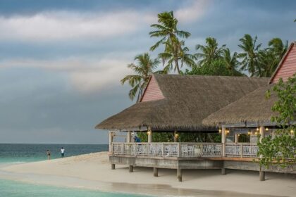 A mesmerising view of a brown hut near a body of turquoise water during the day.