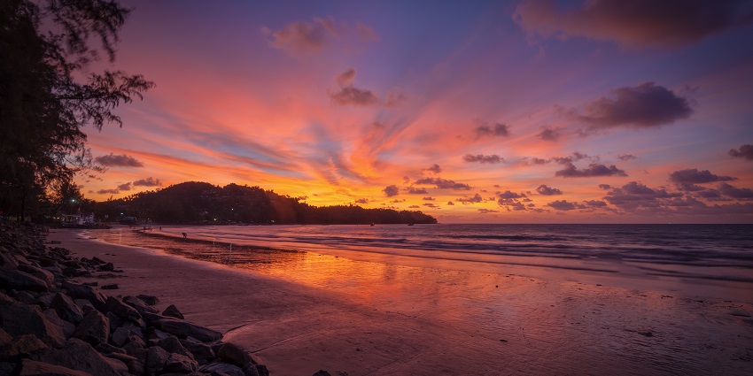 A view of the sun setting down painting the sky with vibrant hues at the Bang Tao Beach.