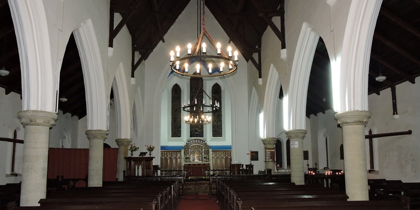 A picture of the ambient interiors of a church in Kasauli with a chandelier in the centre