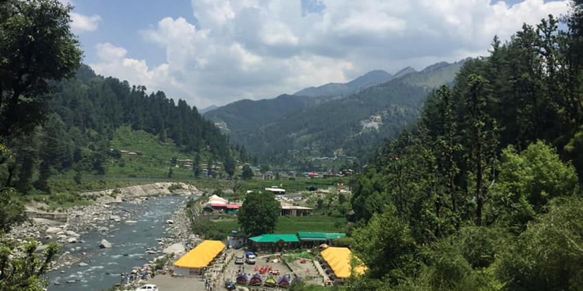 Barot Valley with lush green landscapes, terraced fields, and a tranquil river flowing through.