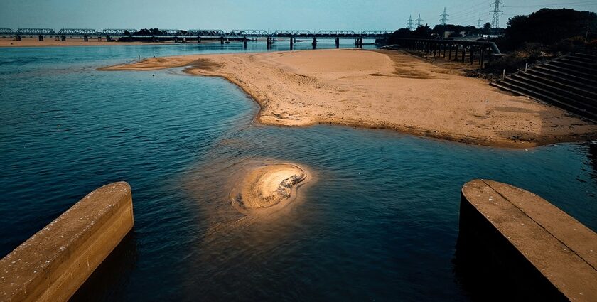 A mesmerising view of a beach with soft sands on the side and a bridge across it.