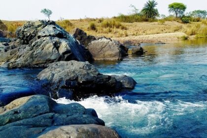 A breathtaking view of a sparkling beach with big and small rocks in it during the day.