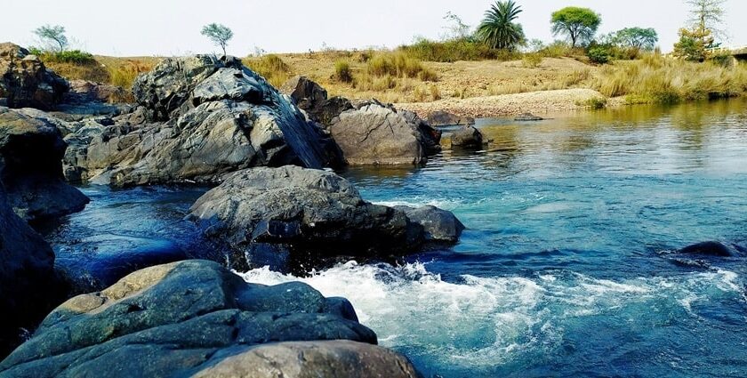 A breathtaking view of a sparkling beach with big and small rocks in it during the day.