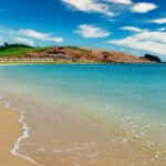 A mesmerising view of the shimmering waters hitting the golden sands near the shoreline.