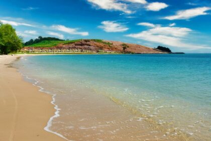 A mesmerising view of the shimmering waters hitting the golden sands near the shoreline.