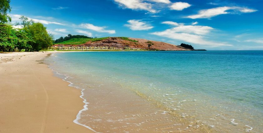 A mesmerising view of the shimmering waters hitting the golden sands near the shoreline.