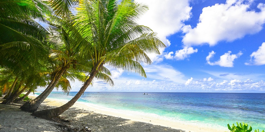Bright sunny day at the beach with golden sands, clear blue waters, and a vibrant sky.