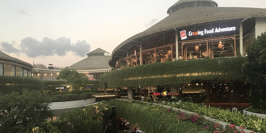 A picture of a shopping mall in Bali with a garden area outside the main entrance