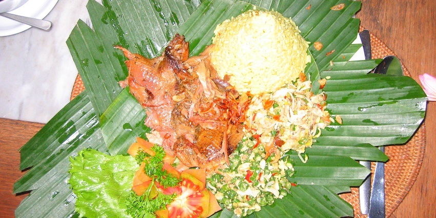 A traditional Balinese dish served on a banana leaf with rice and meat