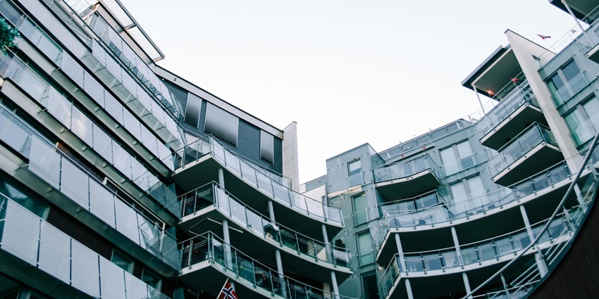 Striking modern geometric glass building with balconies under a clear sky.