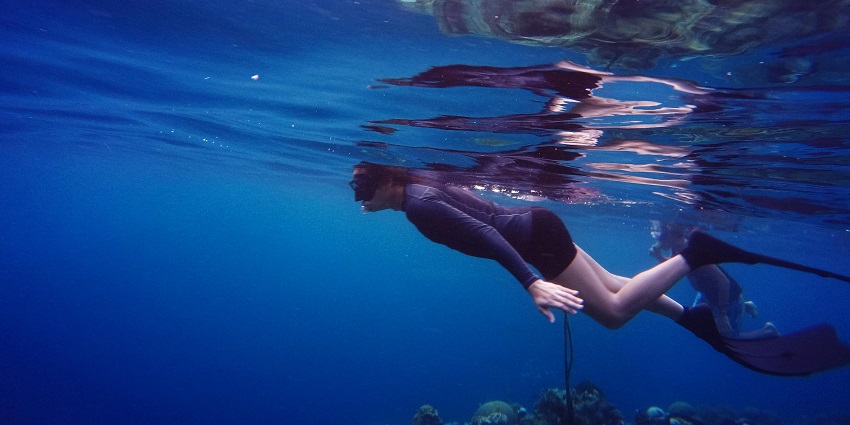 A picture of a lady enjoying scuba diving in Indonesia trying to go deep into the sea