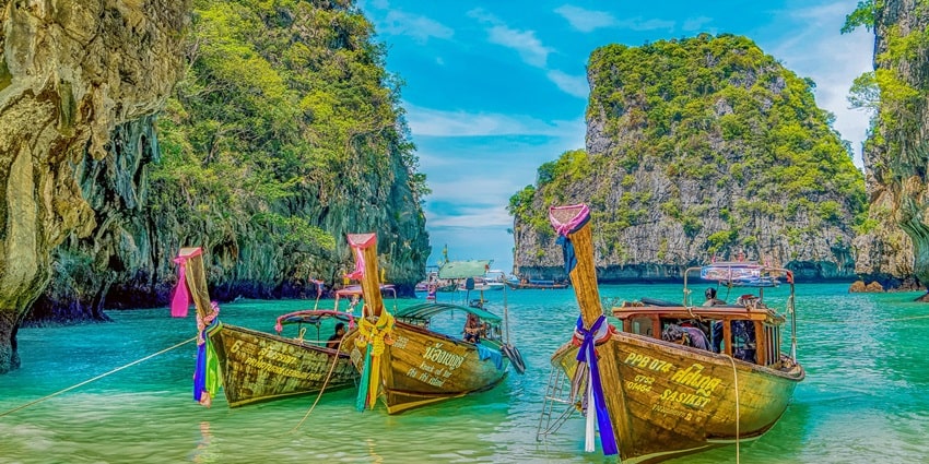 A beautiful picture of a beach in Thailand with boats parked on the shore on a clear day