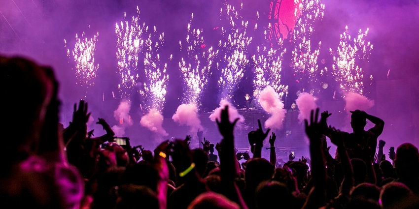 A picture of a music festival with purple lighting and people enjoying