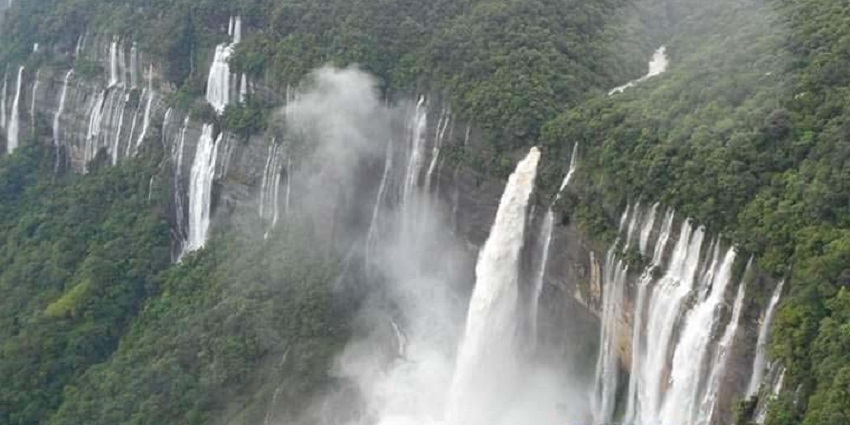 A picture of a waterfall near the beautiful scenery in Meghalaya with trees and greenery