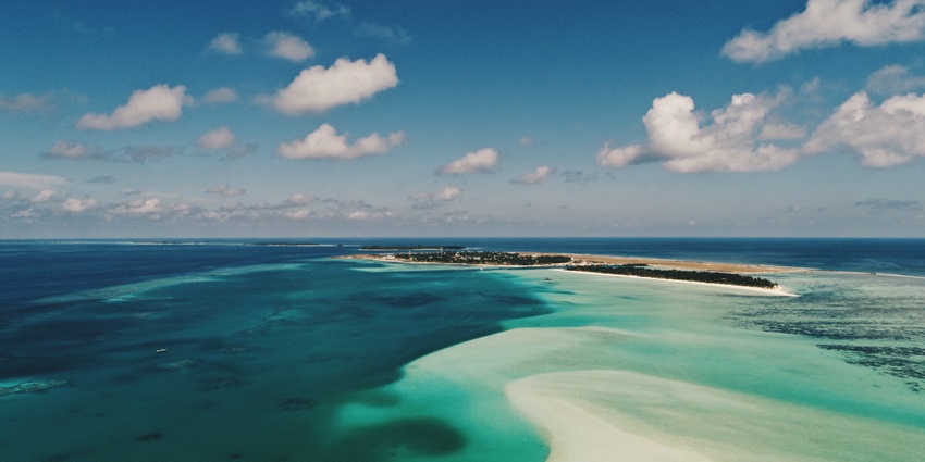 A distant view of a small island in the middle of a blue sea under a clear sky