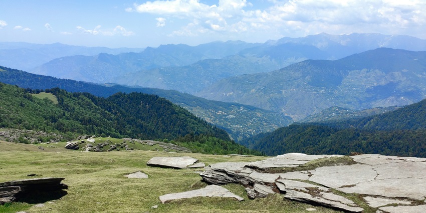 A breathtaking view of lush green valley in Shimla with a mountain range behind.